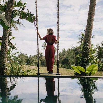 Photo from back of slim woman in long dress looking at rainy sky. Outdoor shot of shapely female model enjoying nature views at resort.
